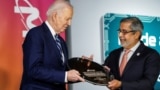 Sanjay Mehrotra, CEO of Micron Technology gives U.S. President Joe Biden a wafer during Biden's visit to the Milton J. Rubenstein Museum of Science and Technology, in Syracuse, New York, April 25, 2024.