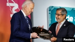 Sanjay Mehrotra, CEO of Micron Technology gives U.S. President Joe Biden a wafer during Biden's visit to the Milton J. Rubenstein Museum of Science and Technology, in Syracuse, New York, April 25, 2024.