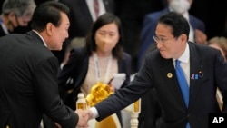 FILE - Japan's Prime Minister Fumio Kishida, right, shakes hands with South Korea's President Yoon Suk Yeol during the ASEAN - East Asia Summit in Phnom Penh, Cambodia, on Nov. 13, 2022. 