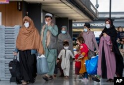 Keluarga yang dievakuasi dari Kabul, Afghanistan berjalan melewati terminal untuk menaiki bus setelah mereka tiba di Bandara Internasional Washington Dulles, AS, 1 September 2021. (Foto: AP)