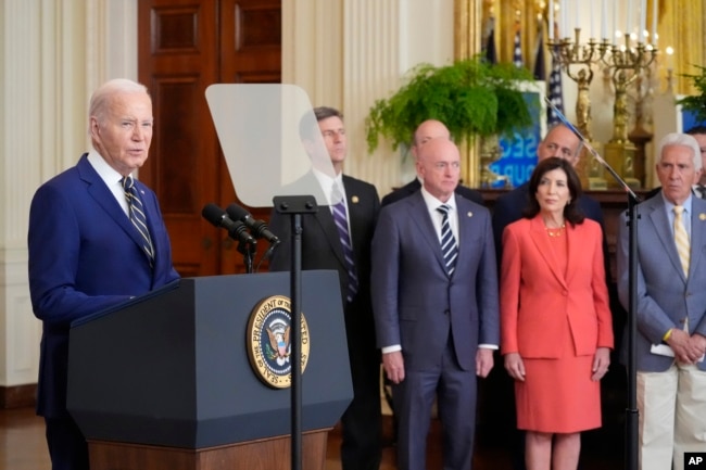 President Joe Biden, left, speaks about an executive order in the East Room at the White House in Washington, Tuesday, June 4, 2024. (AP Photo/Alex Brandon)