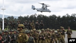 FILE - Tentara Filipina dan Australia berbaris dalam formasi, sementara helikopter marinir AS V-22 Osprey melayang di atas selama latihan militer Alon, di pangkalan angkatan laut kota San Antonio, provinsi Zambales, utara Manila, 25 Agustus 2023. (TED ALJIBE / AFP)