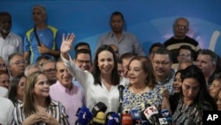 Opposition leader Maria Corina Machado waves as she puts an arm around Corina Yoris in Caracas, Venezuela, March 22, 2024. On Friday, Machado named Yoris as a substitute to her presidential bid while she fights a government ban on her running for office.