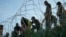 Migrants navigate around concertina wire along the banks of the Rio Grande after crossing from Mexico into the U.S., Aug. 1, 2023, in Eagle Pass, Texas.