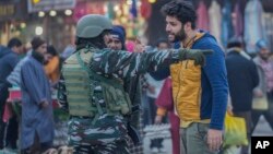 A man talks to an Indian paramilitary soldier standing guard in Srinagar, India-controlled Kashmir, Dec 23, 2023.