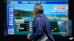 台湾强震后，东京一名男子驻足观看日本一家电视台播放对冲绳地区的海啸警报。(2024年4月3日)