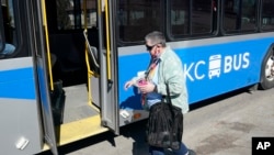 FILE - A woman boards a bus in Kansas City, Mo., March 3, 2021.