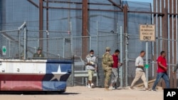 Bajo la vigilancia de un soldado del Ejército de EEUU, migrantes ingresan a El Paso, Texas, desde Ciudad Juárez, México, el 10 de mayo de 2023.