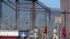 资料照片：2023年5月10日，在一名美国陆军士兵的注视下，移民从墨西哥华雷斯城进入德克萨斯州埃尔帕索。
