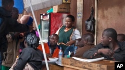 FILE - A woman serves dishes at her food stall that she owns on the edge of a bus terminal in Kampala, Uganda. Experts say much work remains to be done to ensure that African women have equal economic opportunities and are free from discrimination.