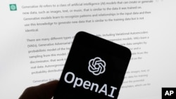 FILE - The OpenAI logo is seen on a mobile phone in front of a computer screen displaying output from ChatGPT, March 21, 2023, in Boston.
