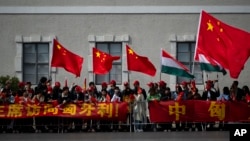 People wave Chinese and Hungarian flags as they wait for the arrival of Chinese President Xi Jinping outside the Buda Castle in Budapest, Hungary, May 9, 2024.