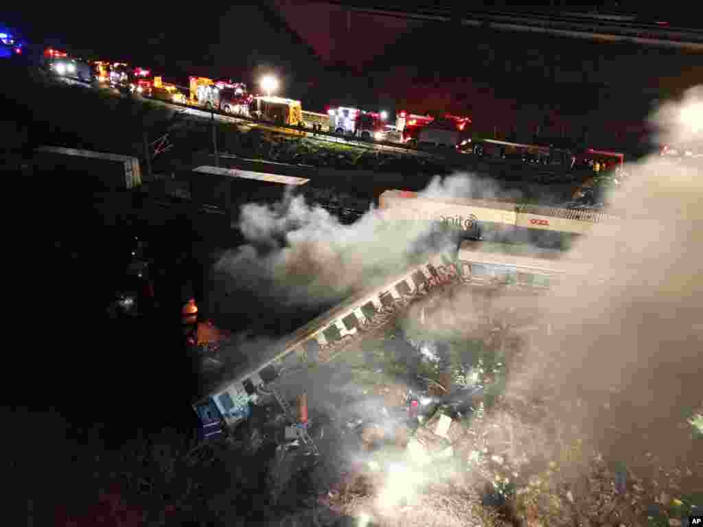 Smoke rises from trains as firefighters and rescuers work after a crash near Larissa city, Greece. A passenger train and a freight train collided head-on in Greece just before midnight Tuesday, killing at least 36 people and injuring scores.