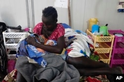 Nyalith Mauit, cradles her day-old son on a bed in the Doctors Without Borders in Bentiu-run hospital in Bentiu, South Sudan, June 24, 2024. She lost the other twin while giving birth.