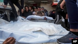 Palestinci utovaruju tijela svojih rođaka ubijenih u izraelskom bombardovanju pojasa Gaze u kamion, koji će biti pokopani na groblju u Deir al Balahu, Pojas Gaze, 25. decembra 2023.
