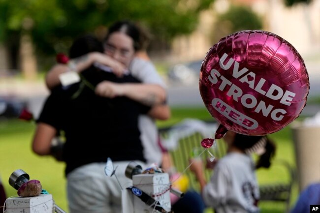 Visitors hug as they place flowers at a memorial in Uvalde, Texas, May 24, 2023. One year ago a gunman killed 19 children and two teachers inside a fourth-grade classroom at Robb Elementary School in Uvalde.