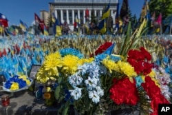 Various flowers are seen in front of a field of flags in memory of fallen fighters, in Kyiv, Ukraine, June 25, 2024. Despite hardships brought by war flowers fill Kyiv and other Ukrainian cities.