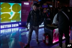 FILE - People gather at a booth set up by Douyin, the Chinese sister app of TikTok, promoting New Year's Eve at an outdoor mall in Beijing, Dec. 23, 2023. In late May 2024, Douyin announced a new verification mechanism for suspected fake content.