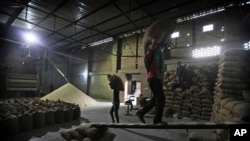 FILE- Laborers stack rice in a private warehouse in Makhu, in the Indian state of Punjab, March 12, 2021. (AP Photo/Manish Swarup, File)