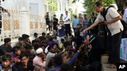 A local official distributes water to Rohingya refugees outside the governor's office in Banda Aceh, Indonesia, Dec. 11, 2023.