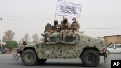 FILE - Taliban fighters patrol on the road during a celebration marking the second anniversary of the withdrawal of US-led troops from Afghanistan, in Kandahar, south of Kabul, Aug. 15, 2023. 