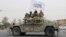 FILE - Taliban fighters patrol on the road during a celebration marking the second anniversary of the withdrawal of US-led troops from Afghanistan, in Kandahar, south of Kabul, Aug. 15, 2023. 