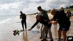 American WWII veteran Bill Wall throws roses into the water during a wreath-laying ceremony at Utah Beach, June 5, 2024, in France's Normandy region.