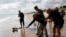American WWII veteran Bill Wall throws roses into the water during a wreath-laying ceremony at Utah Beach, June 5, 2024, in France's Normandy region.