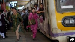 Women rush out of a train during peak hours at Churchgate station in Mumbai, India, March 20, 2023.