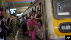 FILE - Women rush out of a train during peak hours at Churchgate station in Mumbai, India, March 20, 2023. Experts say women need to be included in larger numbers at the workplace if they and India are to reap the benefits of development.
