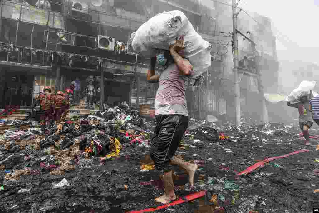 Shopkeepers salvage their goods from nearby shops as a fire rages at a popular market for cheaper clothes in Bangladesh's capital Dhaka, Bangladesh.