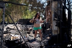 Resident Erika Hernandez looks through the debris of her home, which was destroyed during the Edgehill fire in San Bernardino, Calif., Aug. 6, 2024.