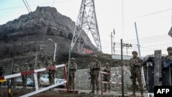 FILE - Azerbaijani servicemen stand guard at a checkpoint at the Lachin corridor as Azerbaijani environmental activists protest what they claim is illegal mining, Dec. 26, 2022. 