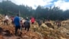 In this photo provided by the International Organization for Migration, people cross over the landslide area to get to the other side in Yambali village, Papua New Guinea, May 24, 2024.