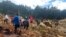 In this photo provided by the International Organization for Migration, people cross over the landslide area to get to the other side in Yambali village, Papua New Guinea, May 24, 2024.