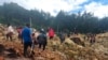 In this photo provided by the International Organization for Migration, people cross over the landslide area to get to the other side in Yambali village, Papua New Guinea, May 24, 2024.