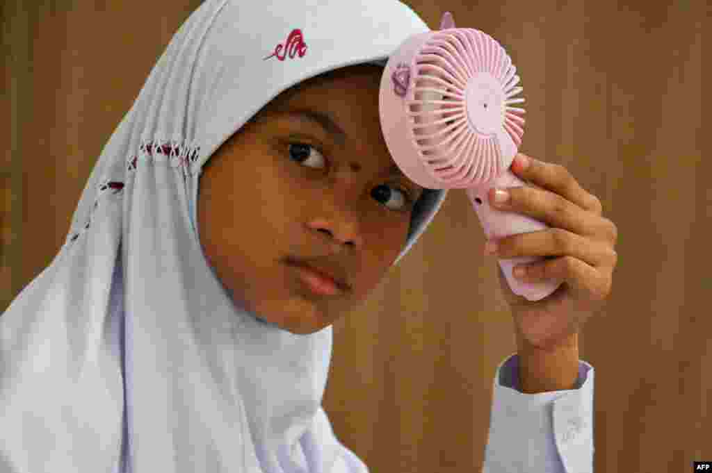 Ученичка се лади со вентилатор по топлото време во Банда Ачех, Индонезија.