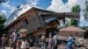 Warga berjalan di samping rumah yang hancur akibat banjir di Desa Nyamukubi, Provinsi Kivu Selatan, di Kongo, Sabtu, 6 Mei 2023.(AP/Moses Sawasawa)