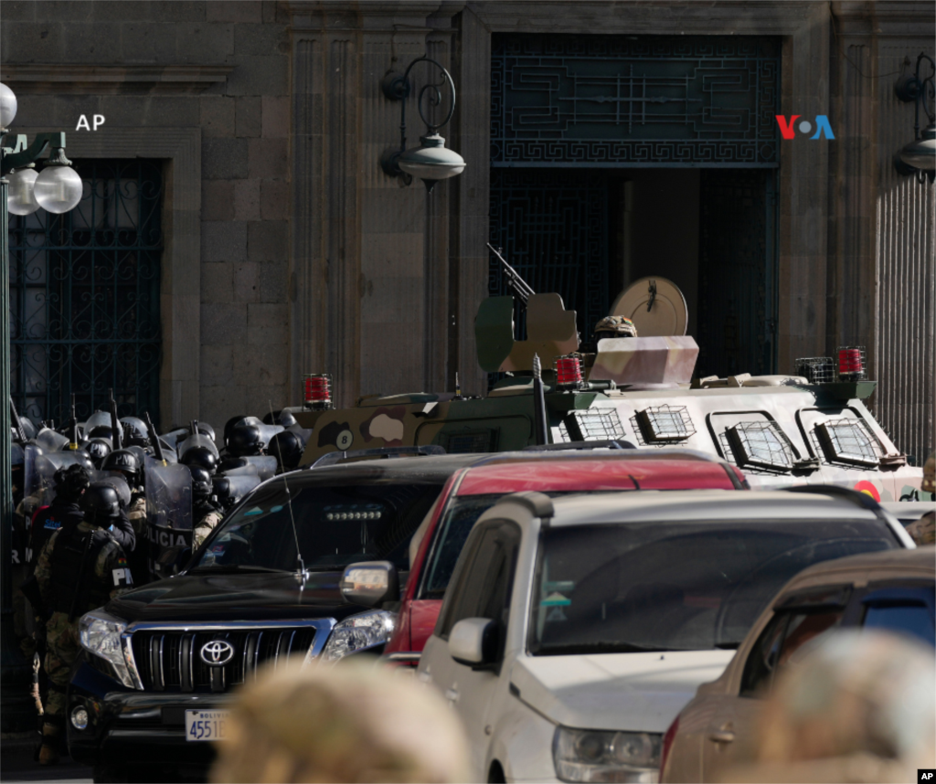  La policía militar se reúne afuera de la entrada principal mientras un vehículo blindado choca contra la puerta del palacio presidencial en la Plaza Murillo de La Paz. 
