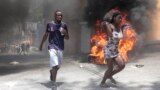 Demonstrators run past tires set on fire during a protest against insecurity in Port-au-Prince, Haiti, Aug. 7, 2023. 
