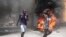 Demonstrators run past tires set on fire during a protest against insecurity in Port-au-Prince, Haiti, Aug. 7, 2023. 