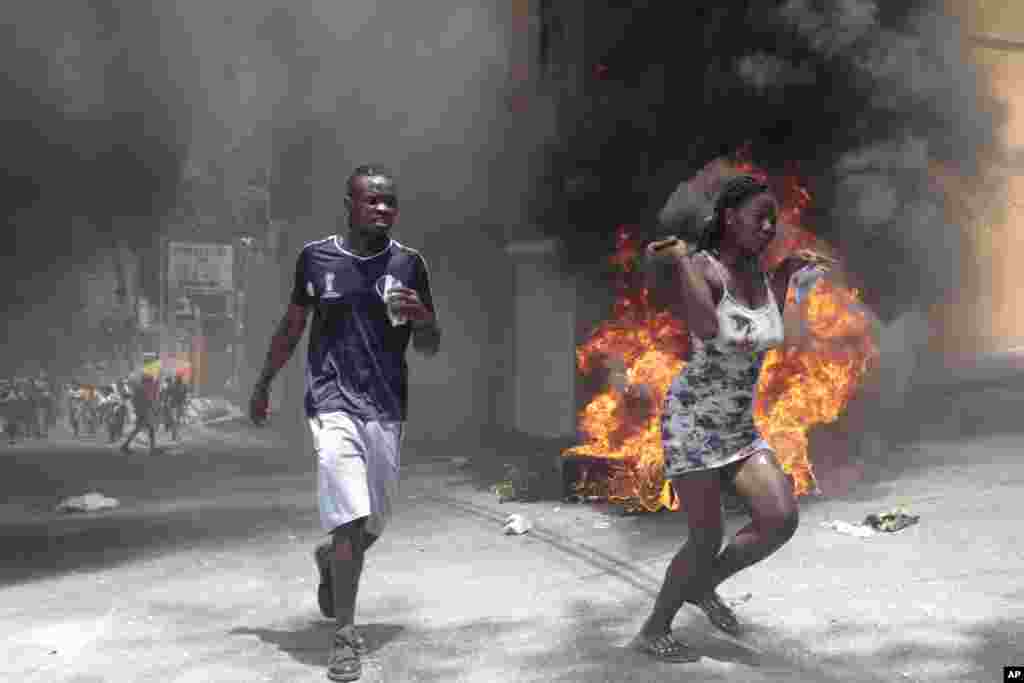 Demonstrators run past tires set on fire during a protest of insecurity in the country, in Port-au-Prince, Haiti, Aug. 7, 2023.