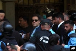 Pakistan's former Prime Minister Imran Khan, center, is escorted by security officials as he arrive to appear in a court, in Islamabad, Pakistan, Friday, May 12, 2023.