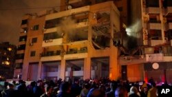 FILE - People gather outside a damaged building following a massive explosion in the southern Beirut suburb of Dahiyeh, Lebanon, January 2, 2024. An explosion killed Saleh Arouri, a top Hamas official and three others, officials for Hamas and Hezbollah said. 