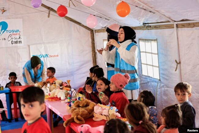 FILE - Volunteers sing with children during an activity to entertain and support the mental health of children affected by the deadly earthquake, at a camp for survivors, in Adiyaman, Turkey, February 18, 2023. (REUTERS/Thaier Al-Sudani/File Photo)