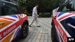 FILE - A man walks past Mini cars decorated with the British flag, outside a showroom in Beijing, China, June 27, 2016.