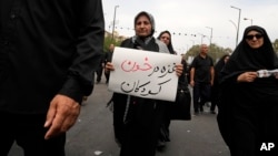 A mourner carries a placard which reads: ' Gaza is in children's blood' during Arbaeen rituals commemorating the end of the 40-day mourning period after the killing of Imam Hussein, Prophet Muhammad's grandson, in A.D. 680, in Shahr-e-Ray, Aug. 25, 2024. 