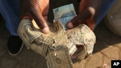 FILE - Tattered $1 U.S. bills are shown at a market in Harare, Zimbabwe, on Oct, 21, 2020. Enterprising traders there repaired the old notes for customers.