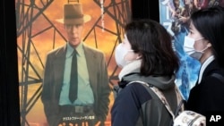 People walk by a poster to promote the movie "Oppenheimer" March 29, 2024, in Tokyo. 