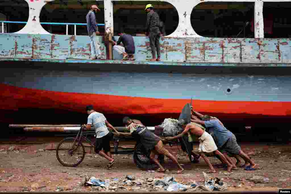 Bangladeshi laborers pull a cart carrying a ferry propeller in a dockyard in Dhaka.